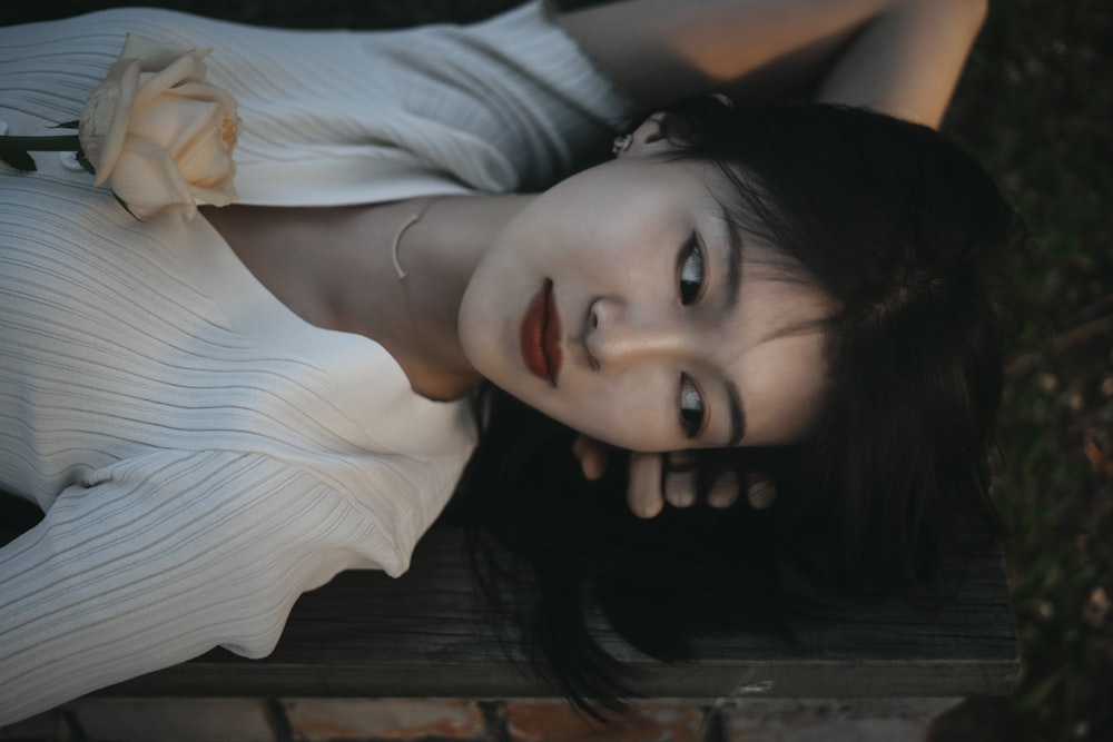 woman in white shirt lying on black wooden bench