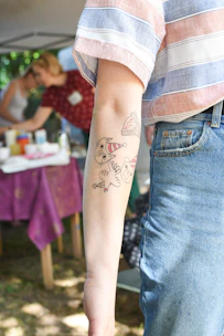person in blue denim shorts with black and red dragon tattoo on right leg