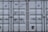 A close-up view of the doors of a shipping container. The surface is metallic with vertical reinforcement bars and stickers indicating information about weight in kilograms and pounds. Labels such as 'MAX. GR. TARE' and 'NET CU. CAP.' are present along with numerical values. The container has a standard industrial appearance.