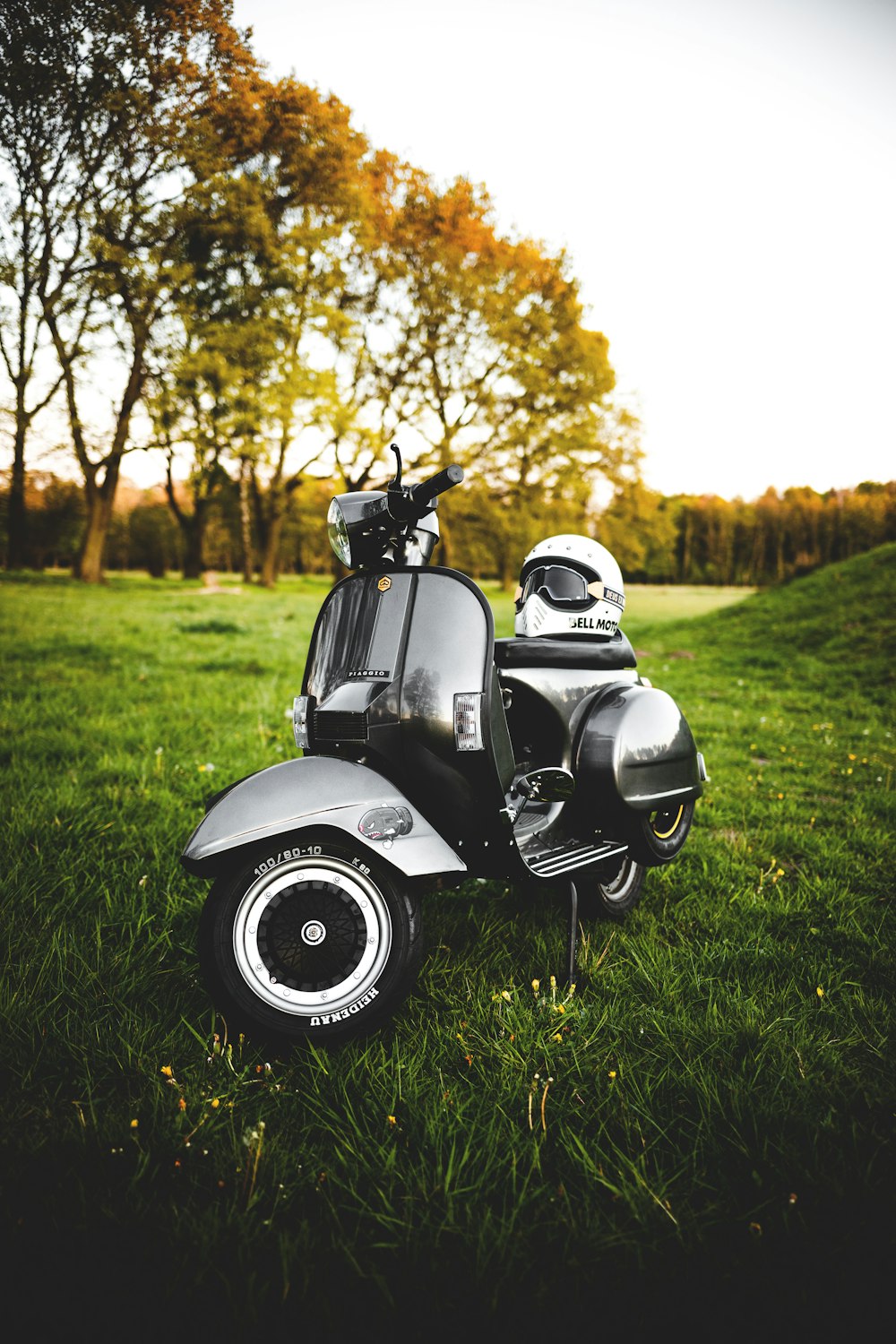 scooter do motor cinza e preto no campo de grama verde durante o dia