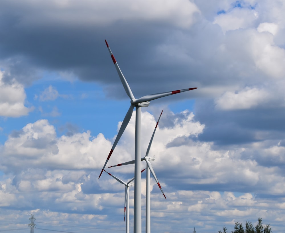 white wind turbine under blue sky and white clouds during daytime