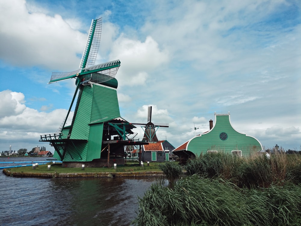 Grüne und braune Windmühle am Fluss tagsüber