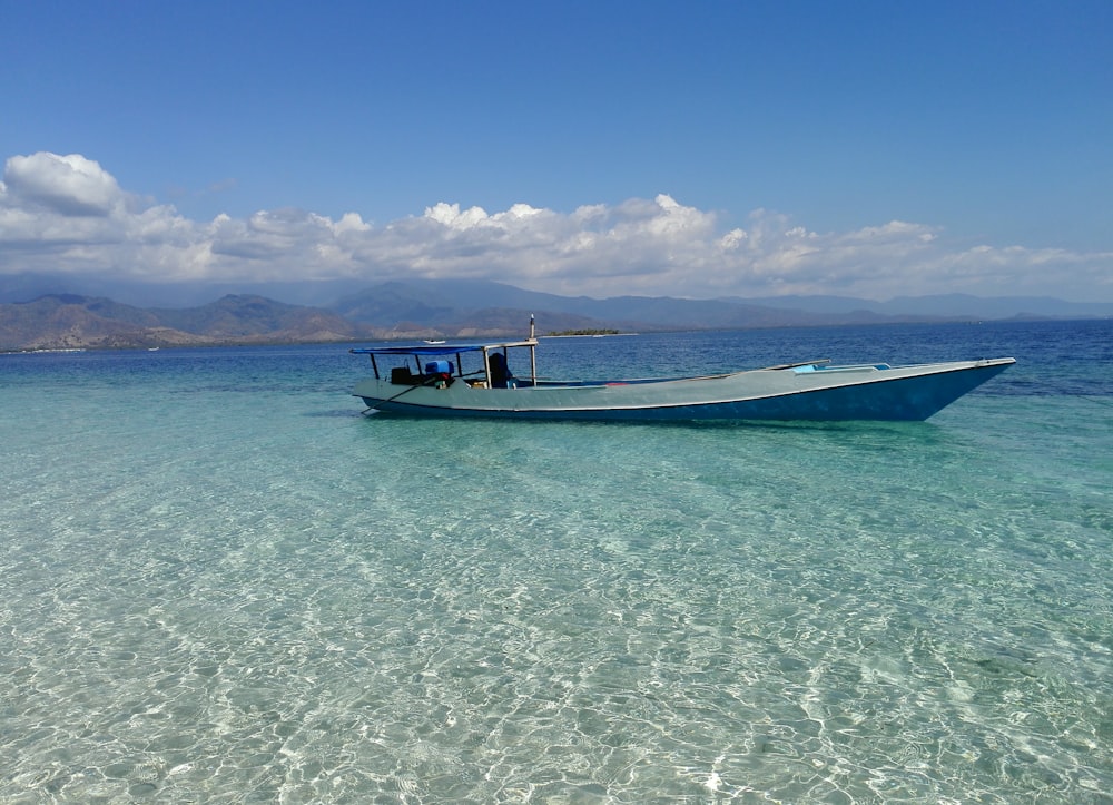 white and black boat on sea under blue sky during daytime