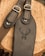 A close-up view of two leather straps with buckles placed on a wooden surface. One of the straps features an embossed design of a deer's head with antlers.