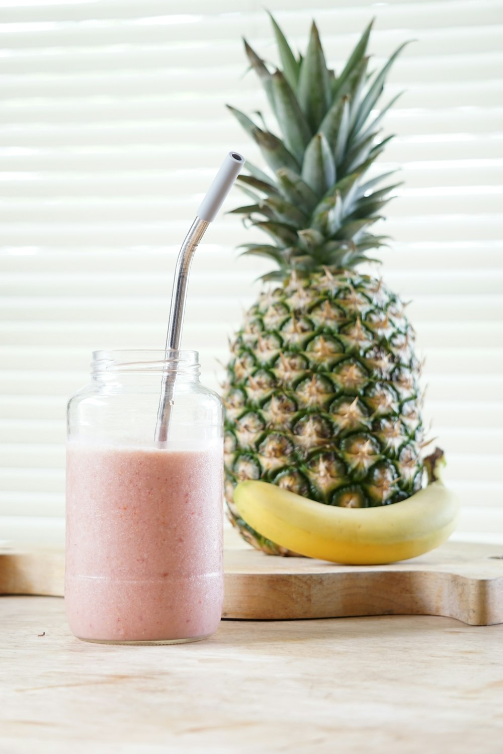 pineapple fruit beside clear drinking glass with red liquid