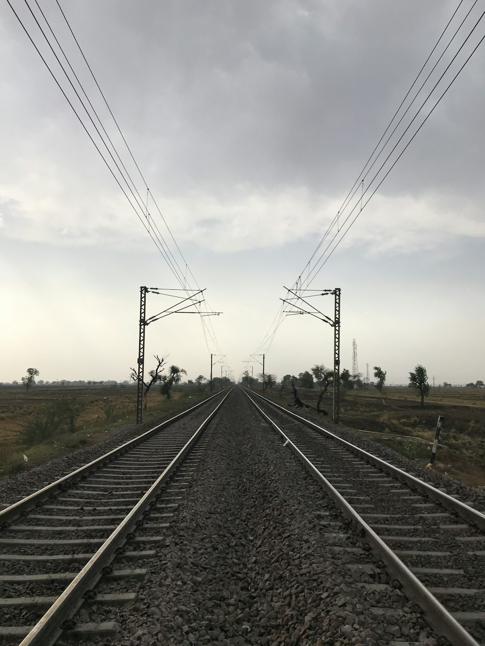 black metal train rail under white clouds during daytime