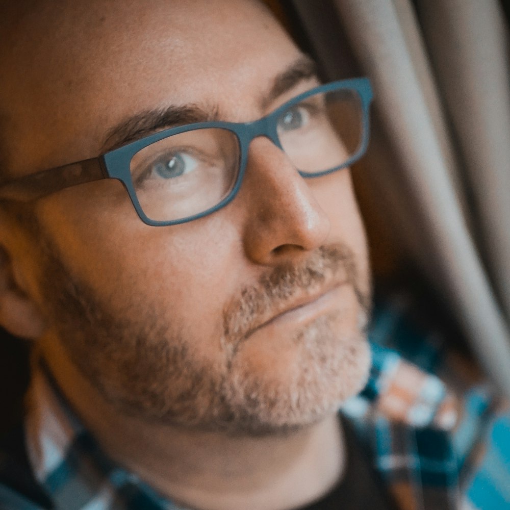 man in blue white and red plaid shirt wearing black framed eyeglasses