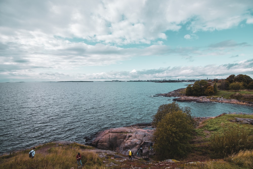 brown rock formation near body of water under white clouds during daytime