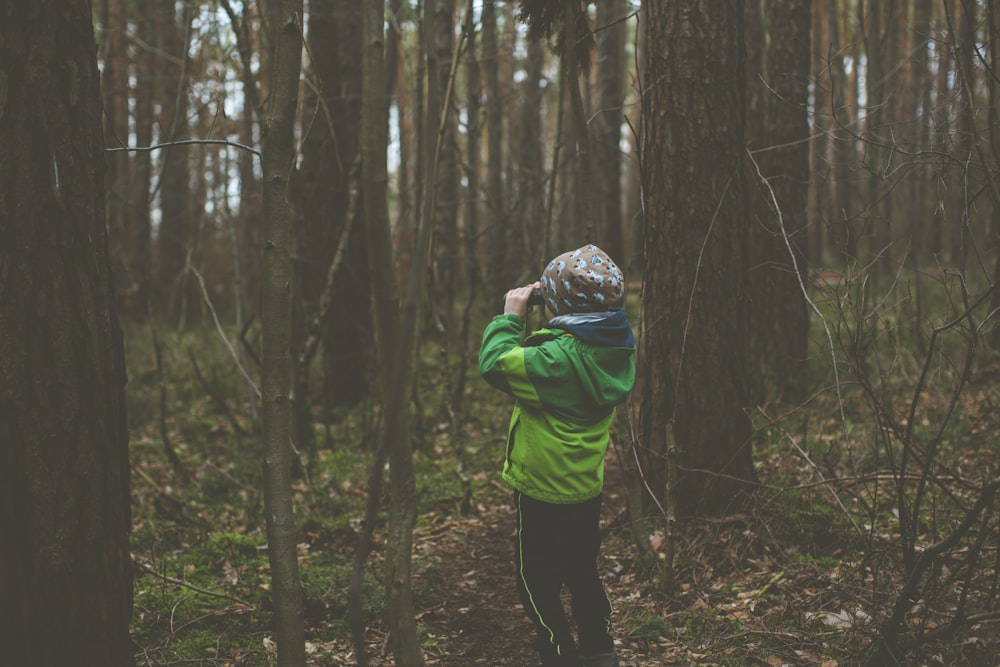 person in green hoodie standing in the woods