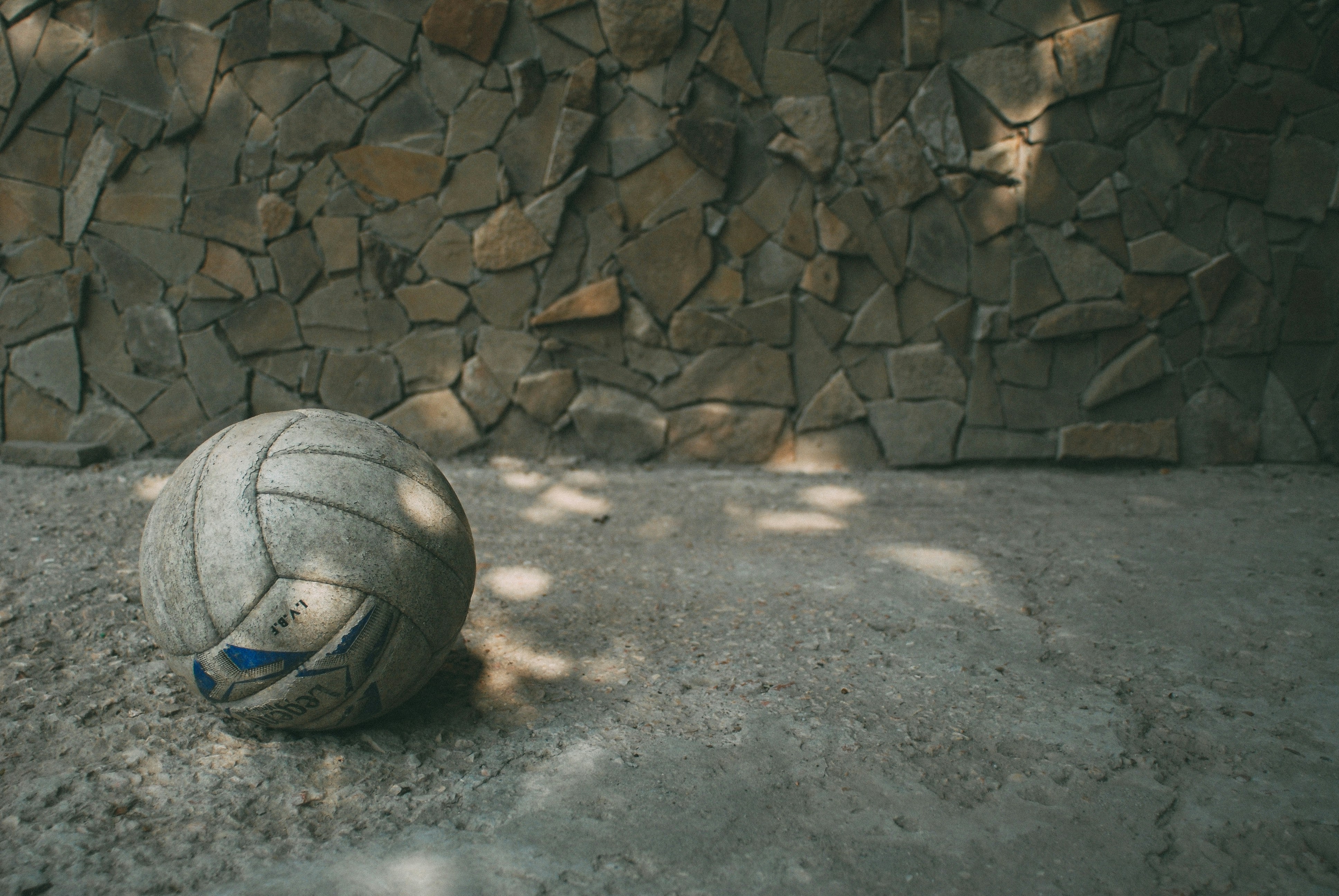 An old volleyball near a stone wall.