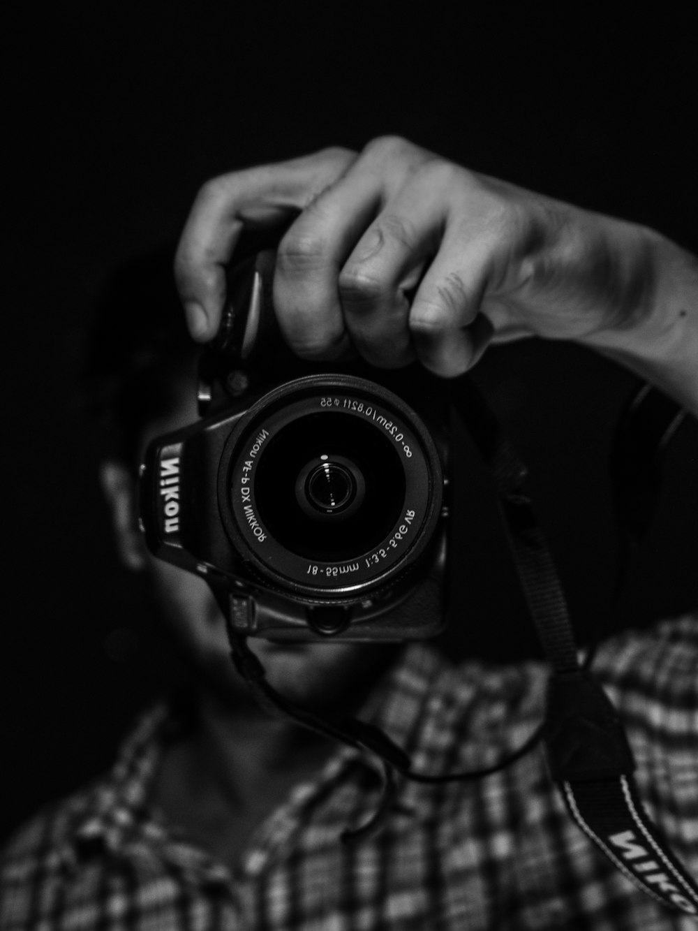 grayscale photo of person holding nikon dslr camera