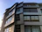 A sleek modern architectural building with dark grey and anthracite tones under a clear sky.