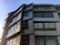 A sleek modern architectural building with dark grey and anthracite tones under a clear sky.