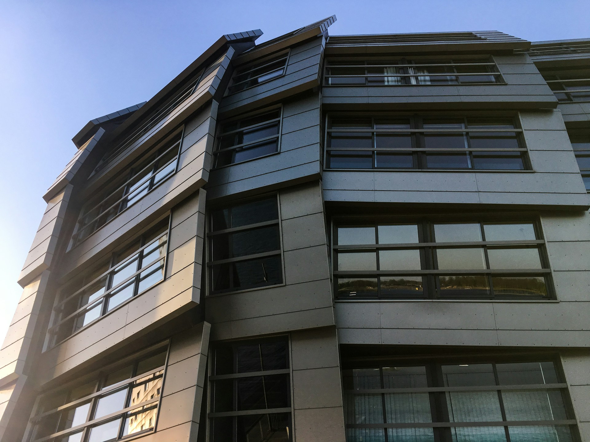 A dramatic exterior view of a contemporary commercial building in Hawthorn, featuring dark grey cladding and bold structural elements against a clear sky.