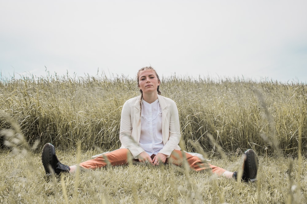 woman in white long sleeve shirt sitting on green grass field during daytime