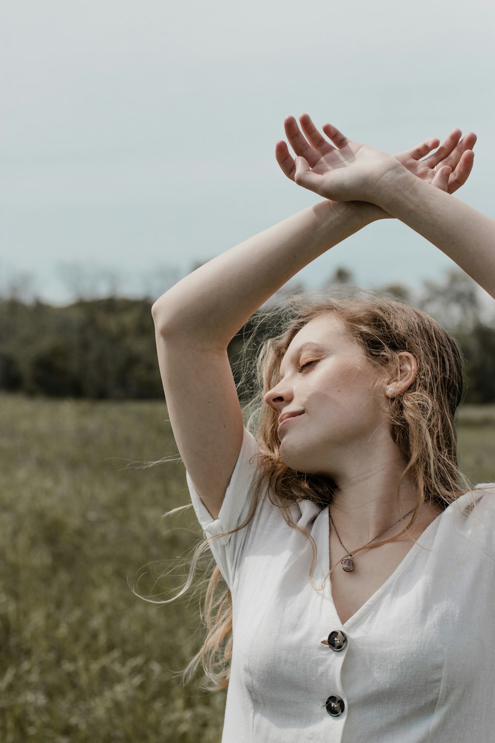 femme en chemise blanche sans manches levant les mains