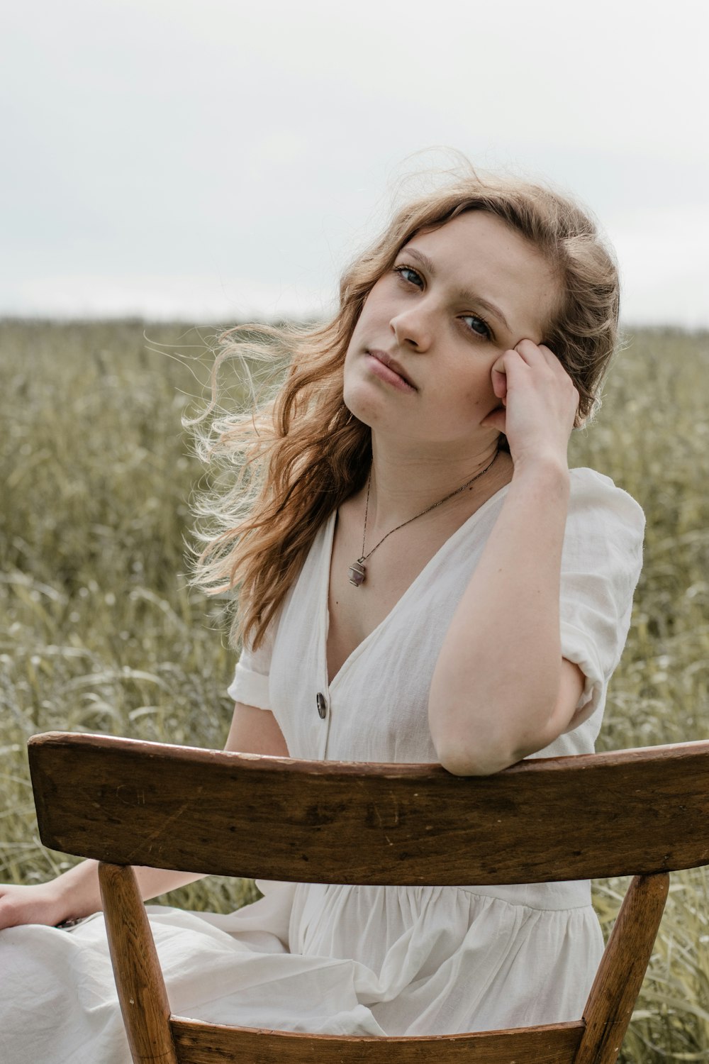 woman in white tank top sitting on brown wooden chair