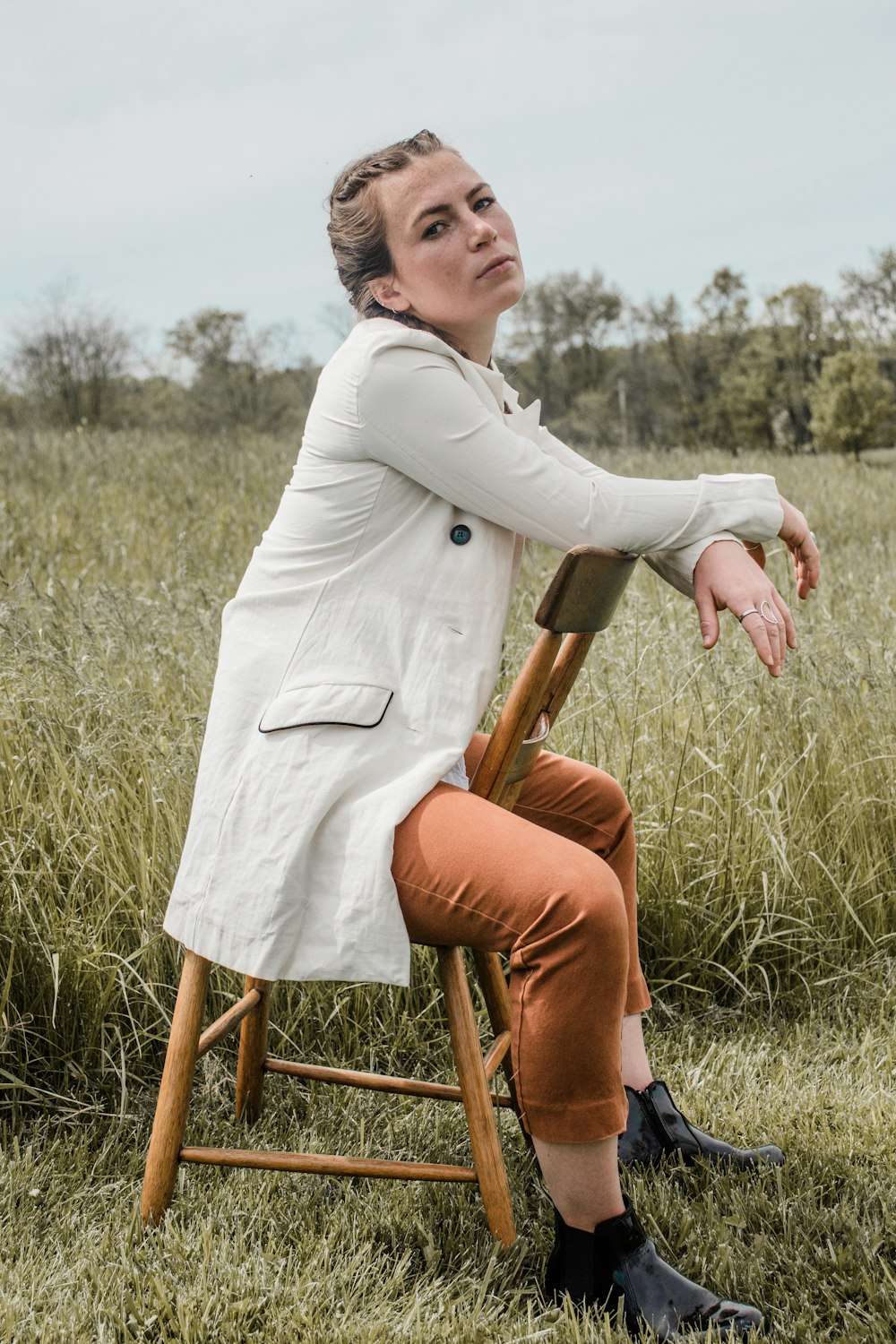woman in white long sleeve shirt and brown pants sitting on brown wooden seat