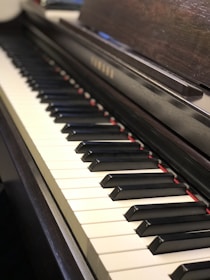 A close-up view of a polished wooden acoustic piano keyboard.