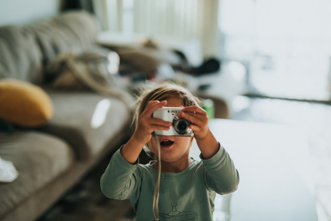 boy in green crew neck t-shirt holding black and silver camera