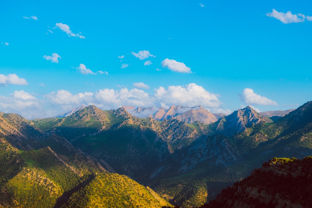 montagne verdi e marroni sotto il cielo blu durante il giorno