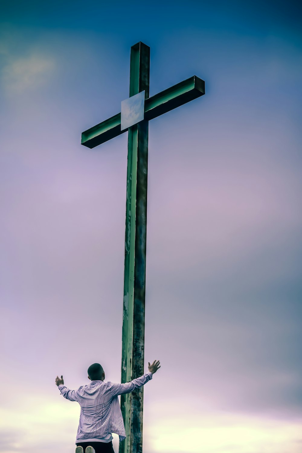 Schwarzes Holzkreuz unter grauem Himmel