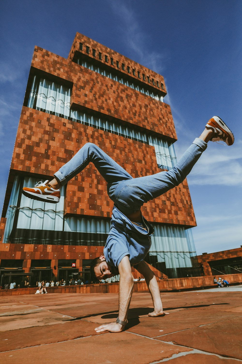 man in black tank top and blue denim jeans jumping on brown wooden roof during daytime