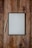 A digital tablet with a black frame rests on a rustic wooden surface, accompanied by a white stylus placed next to it on the left.