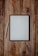 A digital tablet with a black frame rests on a rustic wooden surface, accompanied by a white stylus placed next to it on the left.