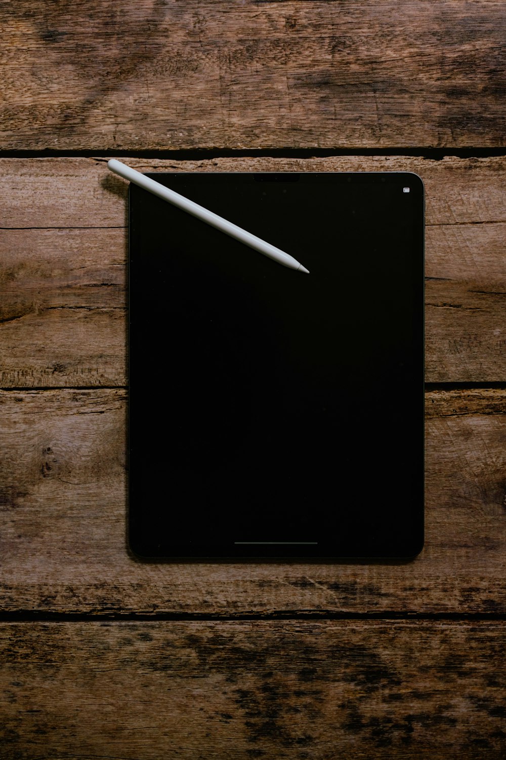 iPad negro sobre mesa de madera marrón