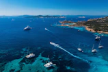 Aerial view of a private yacht cruising near a pristine coastline under clear blue skies.