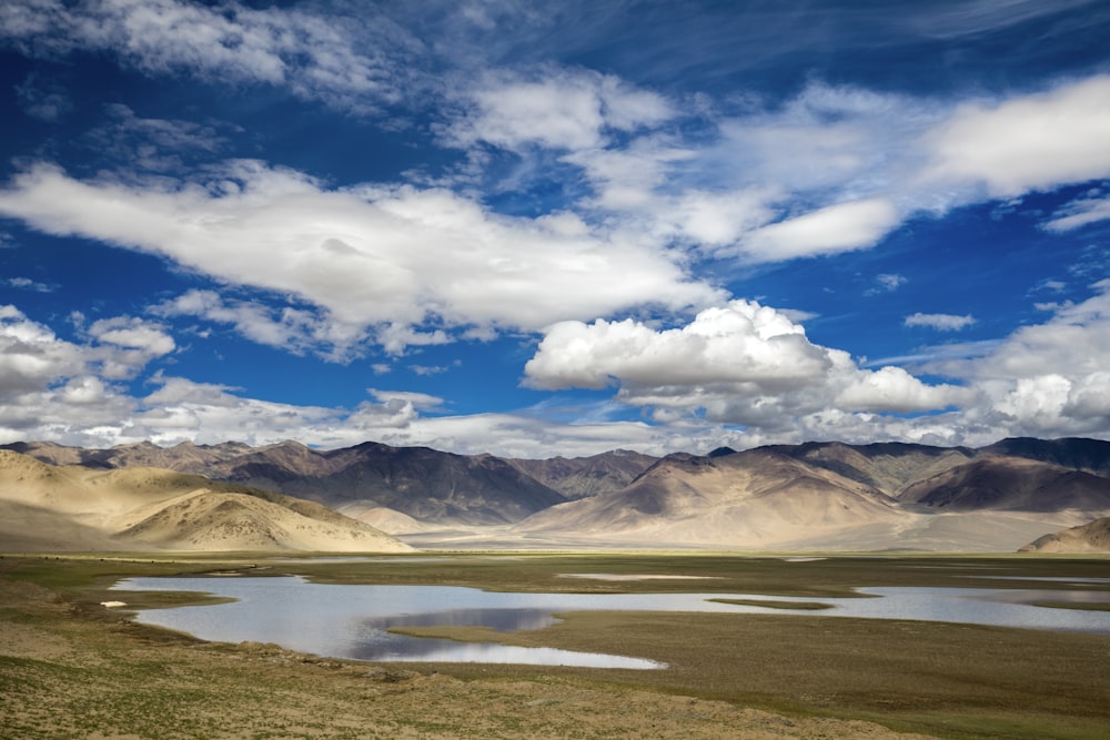 brown and white mountains under white clouds and blue sky during daytime