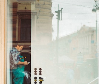 woman in blue denim jacket and blue denim jeans standing in front of glass window