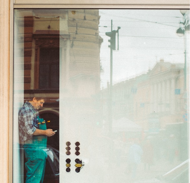 woman in blue denim jacket and blue denim jeans standing in front of glass window