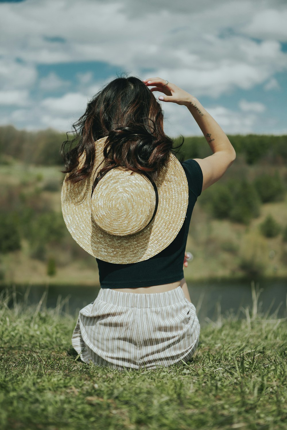 a woman sitting in a field with a hat on her head