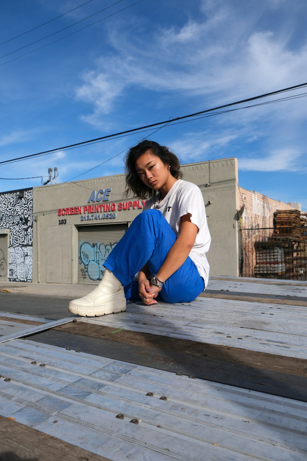 woman in white t-shirt and blue denim jeans sitting on wooden floor