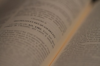 An open book with text in French, focused on a legal article number 1382. The lines are sharp in the middle of the image, while the edges appear slightly blurred due to the depth of field.