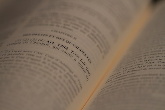 An open book with text in French, focused on a legal article number 1382. The lines are sharp in the middle of the image, while the edges appear slightly blurred due to the depth of field.