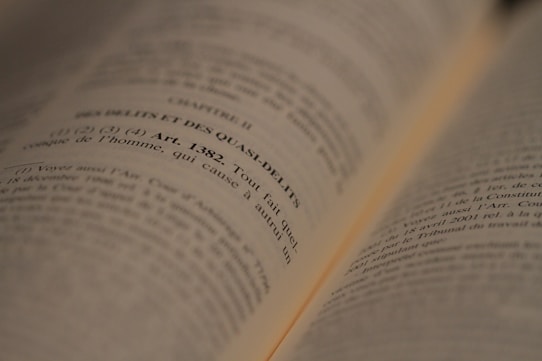 An open book with text in French, focused on a legal article number 1382. The lines are sharp in the middle of the image, while the edges appear slightly blurred due to the depth of field.