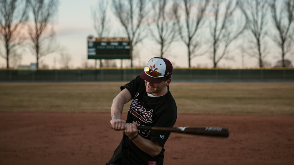 man in black t-shirt playing baseball during daytime