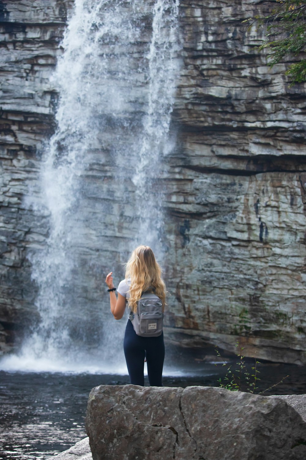 woman in black long sleeve shirt and black leggings standing near waterfalls during daytime