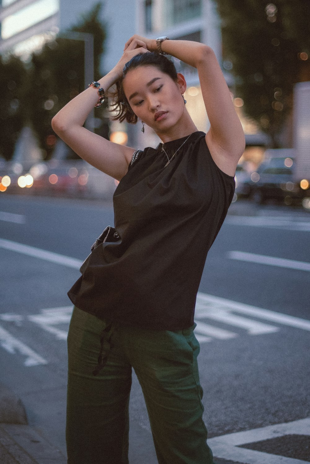 woman in black shirt and green pants standing on road during daytime