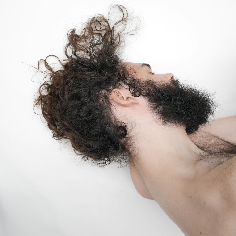 topless man lying on white bed