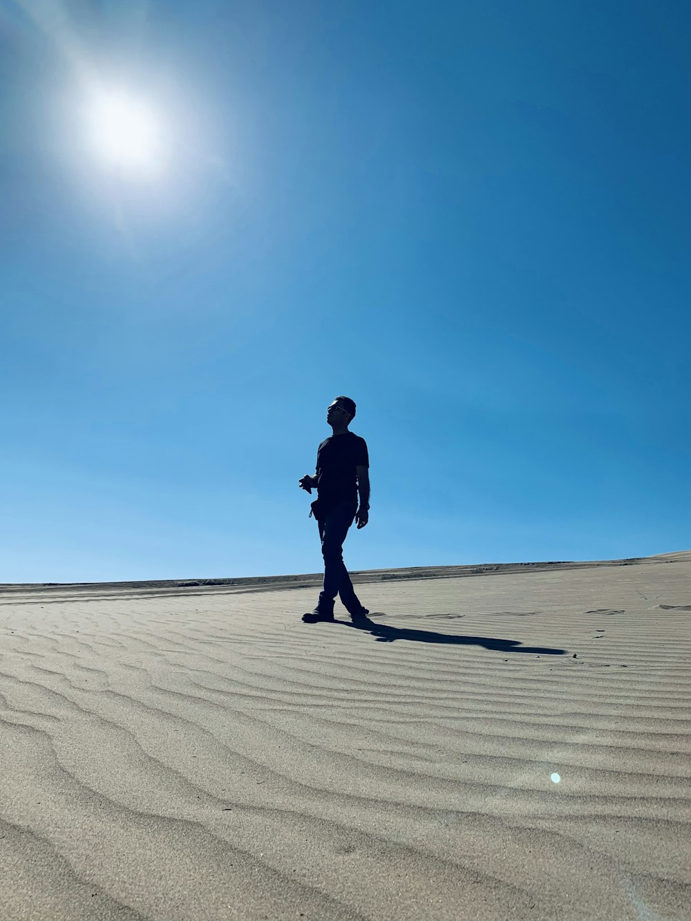 man in black jacket walking on sand during daytime