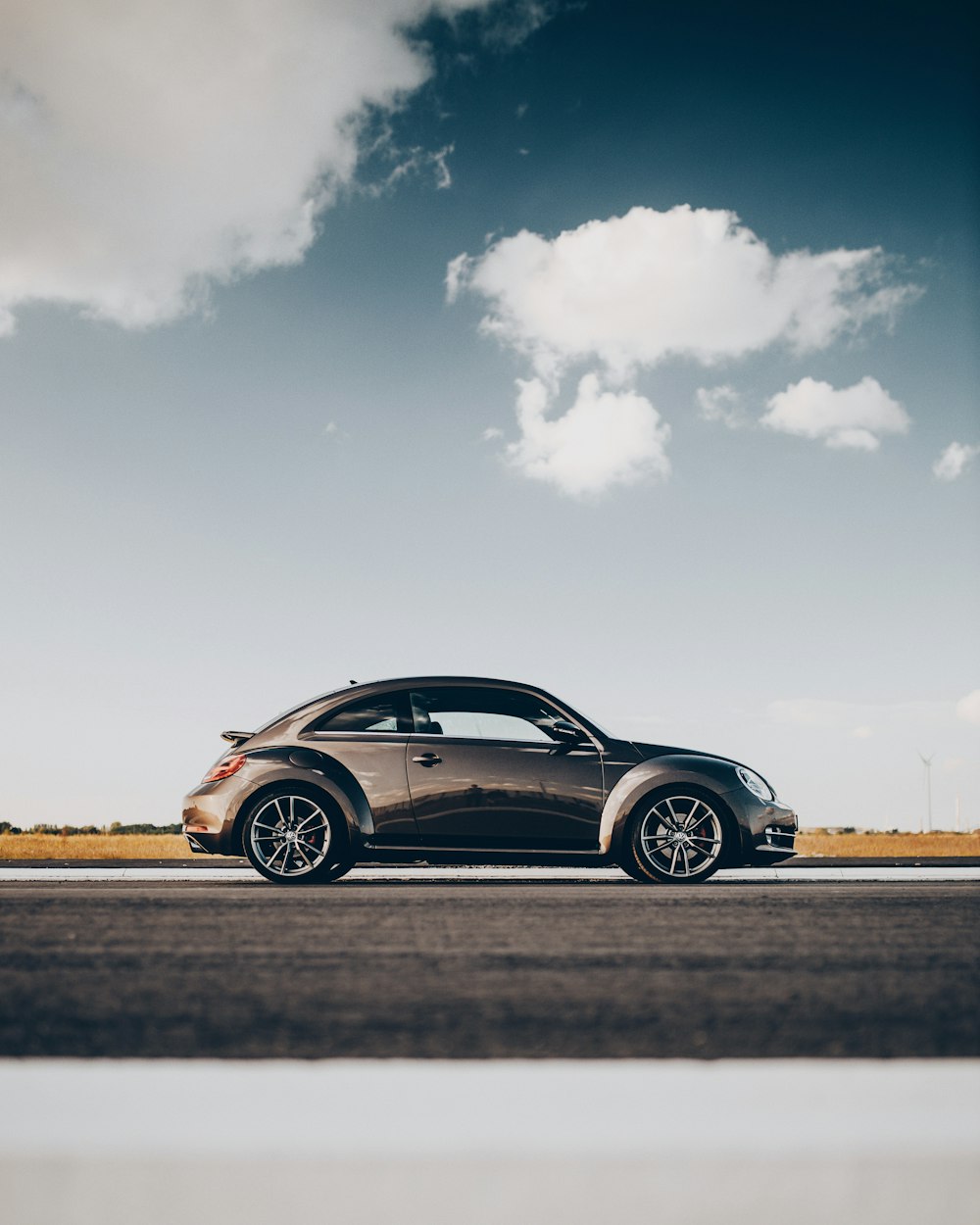 black coupe on brown field under white clouds and blue sky during daytime