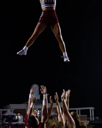 A vibrant photo of Indiana Invasion Cheer team members practicing a group stunt outdoors with smiles and energy.