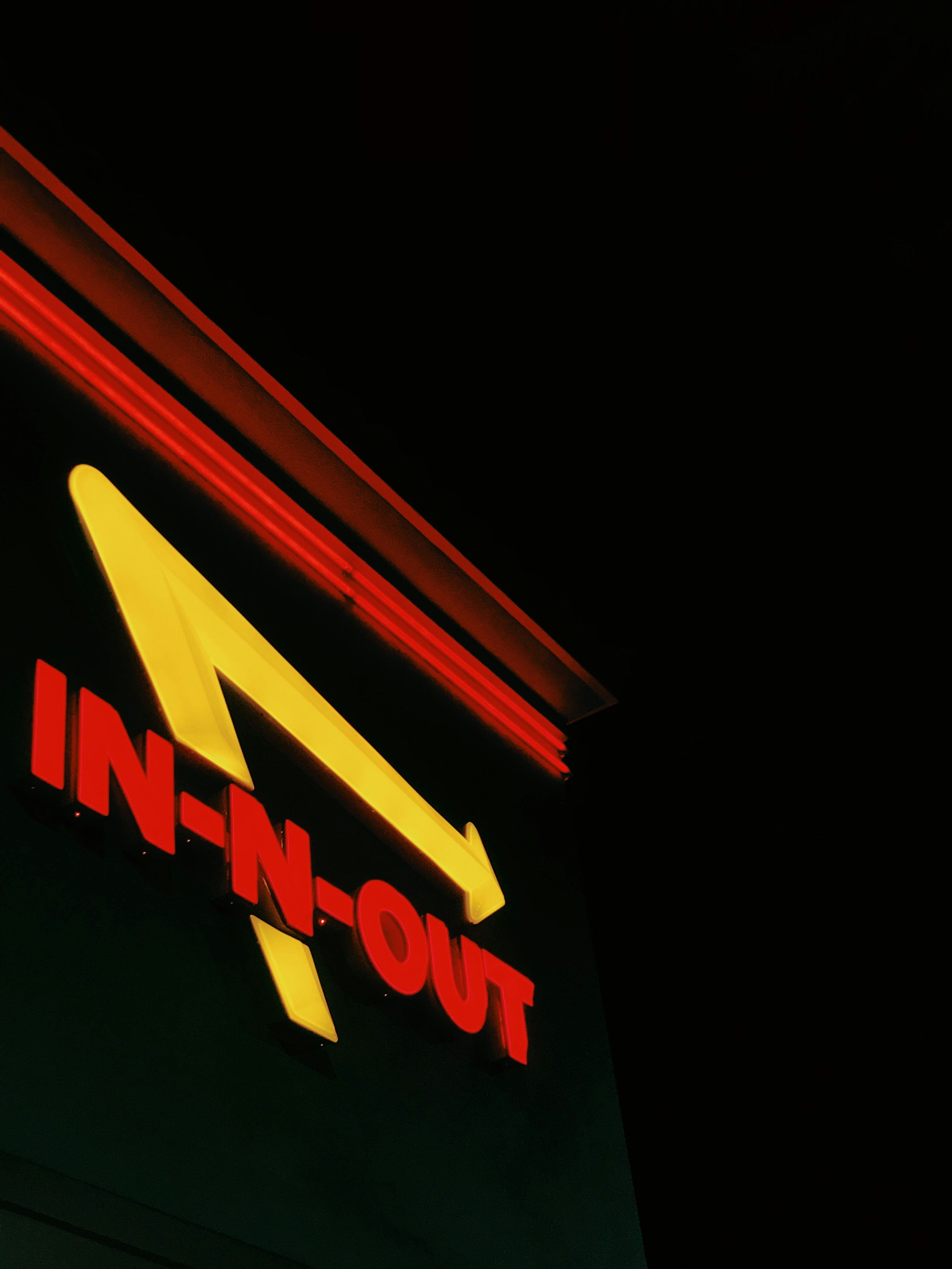 A neon sign that reads in - n - out on the side of a building photo ...