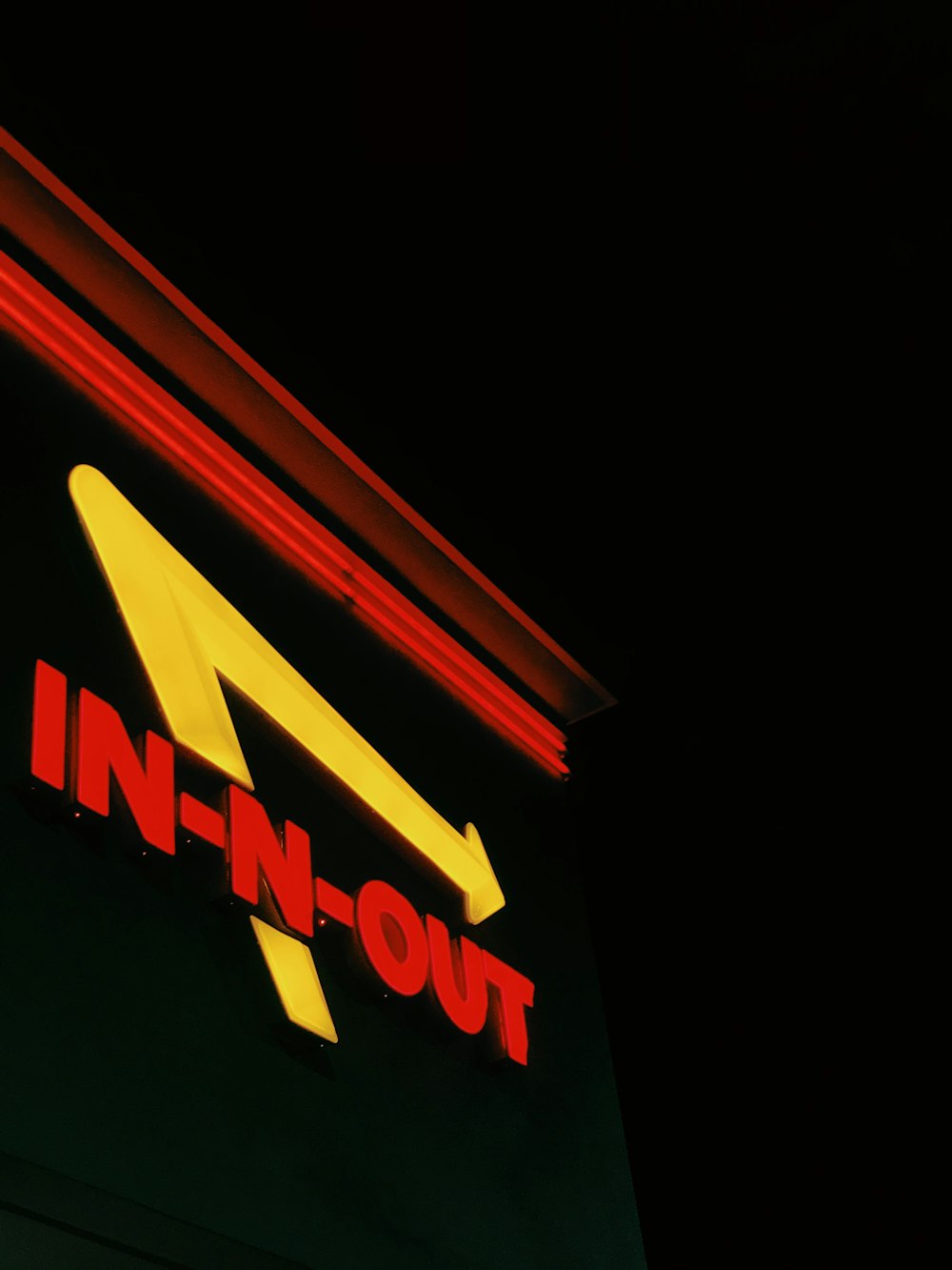 a neon sign that reads in - n - out on the side of a building