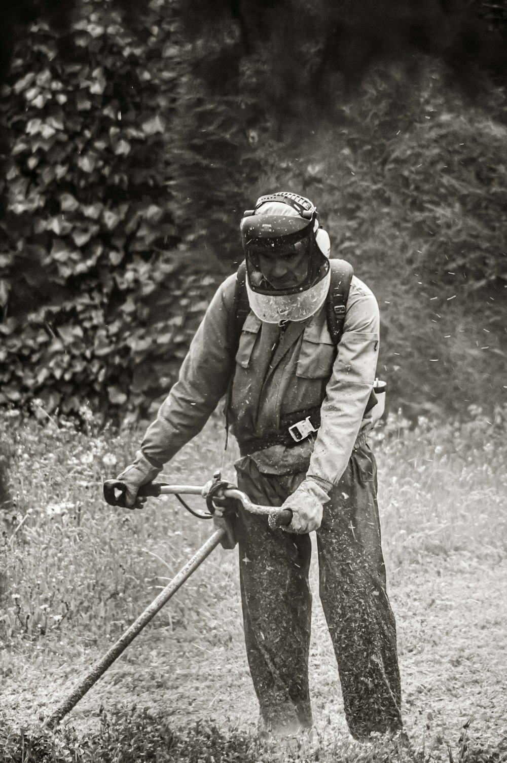 grayscale photo of man in jacket and helmet riding bicycle