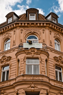 A historic building facade with ornate architectural detailing and multiple windows. The structure features elaborate embellishments around the windows and a curved balcony. A banner is displayed on the balcony with a message related to solidarity.